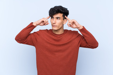 Young Argentinian man over isolated blue background having doubts and thinking