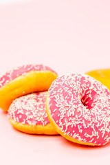 Four donuts in a pink glaze with a white sprinkles on a pink background. Sweets and desserts. Minimalistic background with clean place for the inscription. Copy space.