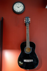 Acoustic guitar, hanging on the red wall