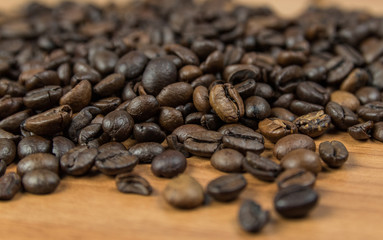 close up view of piled up roasted coffee beans on a wooden surface