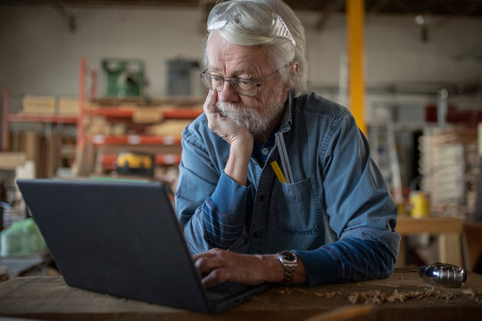 Portrait of senior man using laptop in carpentry workshop