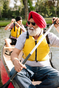 Mature Indian man canoeing with son