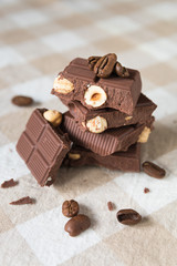 pieces of chocolate with hazelnuts and coffee beans on a brown tablecloth