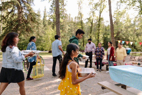 Indian family carrying Food to picnic table in park