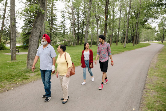 Indian Family Walking On Path In Park