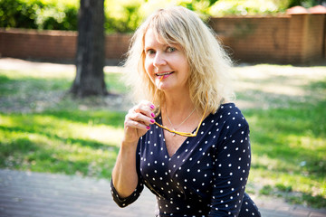 Portrait mature woman. Beautiful smiling blonde outside. Smiling woman in spring city,