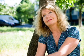 Portrait mature woman. Beautiful smiling blonde outside. Smiling woman in spring city, 50-55 years
