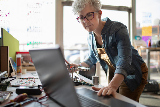 Mature woman using laptop in maker space
