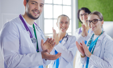 Happy medical team comprising male and female doctors smiling broadly and giving a thumbs up of success and hope