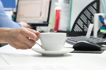 White tea cup on the table near the computer in the office