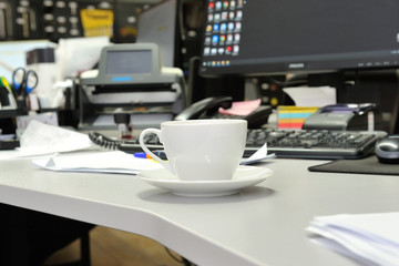 White tea cup on the table near the computer in the office