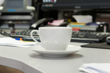 White tea cup on the table near the computer in the office