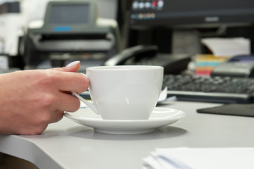 White tea cup on the table near the computer in the office
