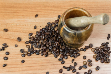 close up shot of mortar and pestle crushing coffee beans against wooden background