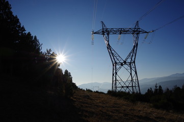 Poteau en métal de ligne électrique d'énergie de haute tension en montagne et ciel bleu