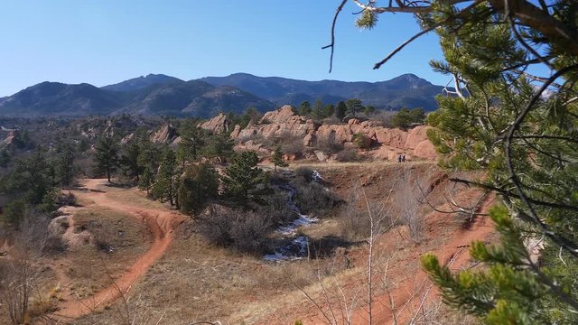 Reveal shot, from behind an evergreen, of Red Rock open space in Colorado Springs, Colorado
