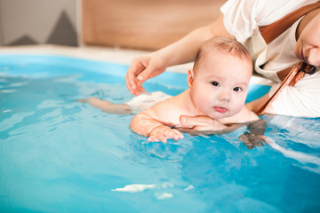 Litle baby in pool swimming bathing during health procedures.
