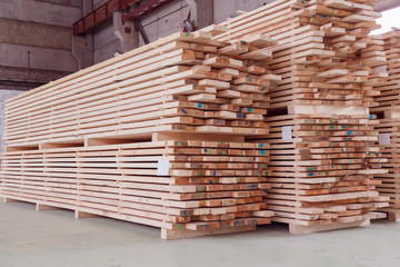 Warehouse or factory for sawing boards on sawmill indoors. Wood timber stack of wooden blanks construction material. Logging Industry.