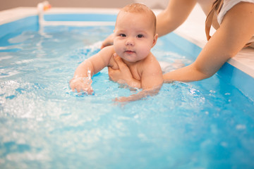 Fototapeta na wymiar Litle baby in pool swimming bathing during health procedures.