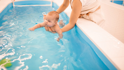 Litle baby in pool swimming bathing during health procedures.