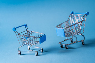 Empty miniature shopping carts on blue background.