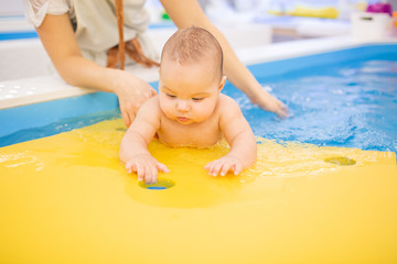 Litle baby in pool swimming bathing during health procedures.