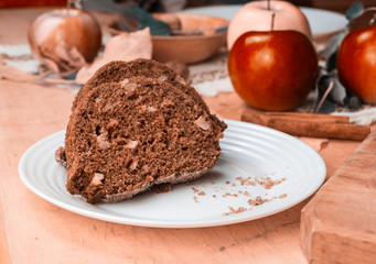 Sliced apple cinnamon bread with decorations on wooden table. Made from apples, sugar, oil, eggs, flour. Homemade apple loaf cake on plate with fresh apples and cinnamon in background at autumn