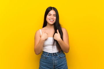 Young teenager Asian girl over isolated yellow background with surprise facial expression