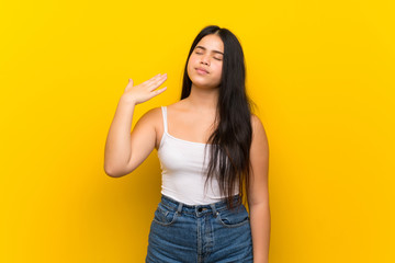 Young teenager Asian girl over isolated yellow background with tired and sick expression