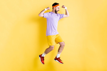 side view of excited bearded sportsman jumping on yellow