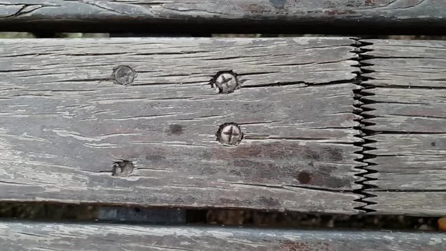 Slow motion slide over old rotting grey wooden floor beams nailed down with interlocking joints  patio flooring.