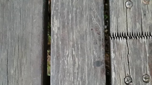 Slow motion slide over old rotting grey wooden floor beams nailed down with interlocking joints  patio flooring.