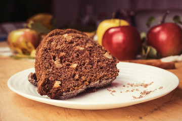 Sliced apple cinnamon bread with decorations on wooden table. Made from apples, sugar, oil, eggs, flour. Homemade apple loaf cake on plate with fresh apples and cinnamon in background at autumn