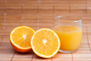 glass of orange juice and oranges on wooden table