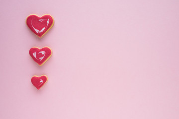 Decorated cookies of various sizes in the shape of a heart, on a pink background. Copy space. Valentine's Day concept.