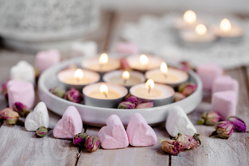 Obraz na płótnie Canvas Saint Valentine's day celebration. Cute romantic surprise for a special day. Rustic wooden background, candles, sweets, flowers. Close up
