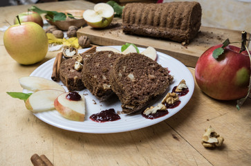 Sliced apple cinnamon bread with decorations on wooden table. Made from apples, sugar, oil, eggs, flour. Homemade apple loaf cake on plate with fresh apples and cinnamon in background at autumn