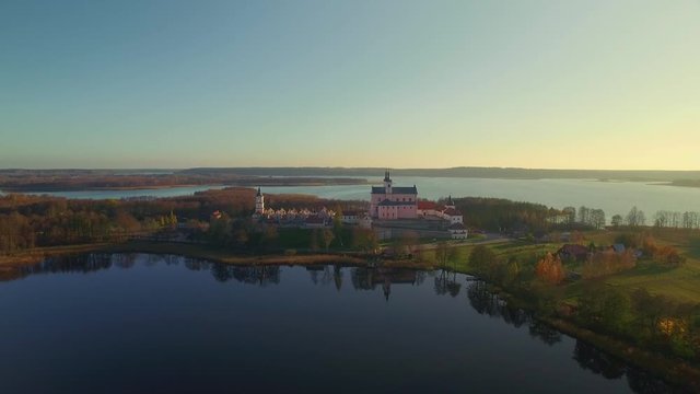 Aerial view of Camaldolese monastery by lake, Suwalszczyzna, Poland, backward shot