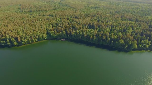 Aerial view of emerald forest lake, Suwalszczyzna, Poland, approach shot