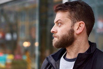Obraz premium Portrait of a Brazilian man with a beard with a serious face in the city, bokeh lights behind him