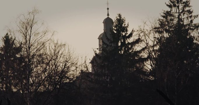Cormorant bird flies towards the sunset and passes an old european church. High quality 4k slowmotion footage.