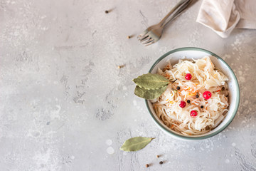 Fermented cabbage with cranberry in ceramic bowl over light grey stone background. Homemade sauerkraut with cranberry and black pepper. Probiotics food concept. Preserved vegetarian diet. 