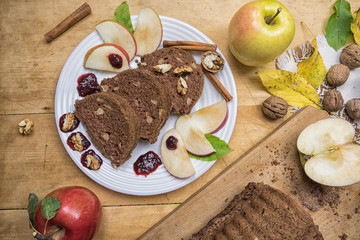 Sliced apple cinnamon bread with decorations on wooden table. Made from apples, sugar, oil, eggs, flour. Homemade apple loaf cake on plate with fresh apples and cinnamon in background at autumn