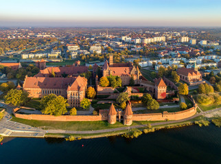 Fototapeta na wymiar Medieval Malbork (Marienburg) Castle in Poland, main fortress of the Teutonic Knights at the Nogat river. Aerial skyline view of the city in fall in sunset light