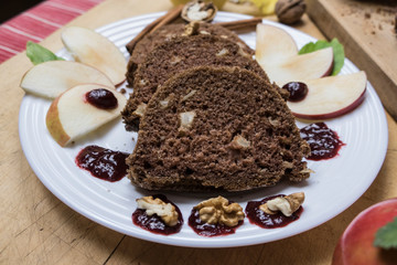 Sliced apple cinnamon bread with decorations on wooden table. Made from apples, sugar, oil, eggs, flour. Homemade apple loaf cake on plate with fresh apples and cinnamon in background at autumn