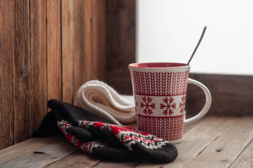 mug with mittens on a wooden windowsill in winter