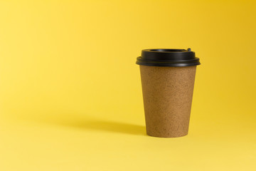 Coffee take away mockup. Kraft paper coffee cup on yellow background. Copy space.