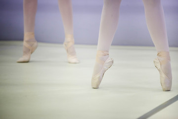  legs of a ballerina in white tights and beige pointes at a training session in the gym