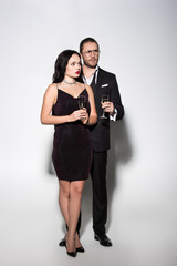 beautiful couple in suit and dress holding champagne glasses for valentines day on white