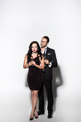 young couple in suit and dress holding champagne glasses for valentines day on white